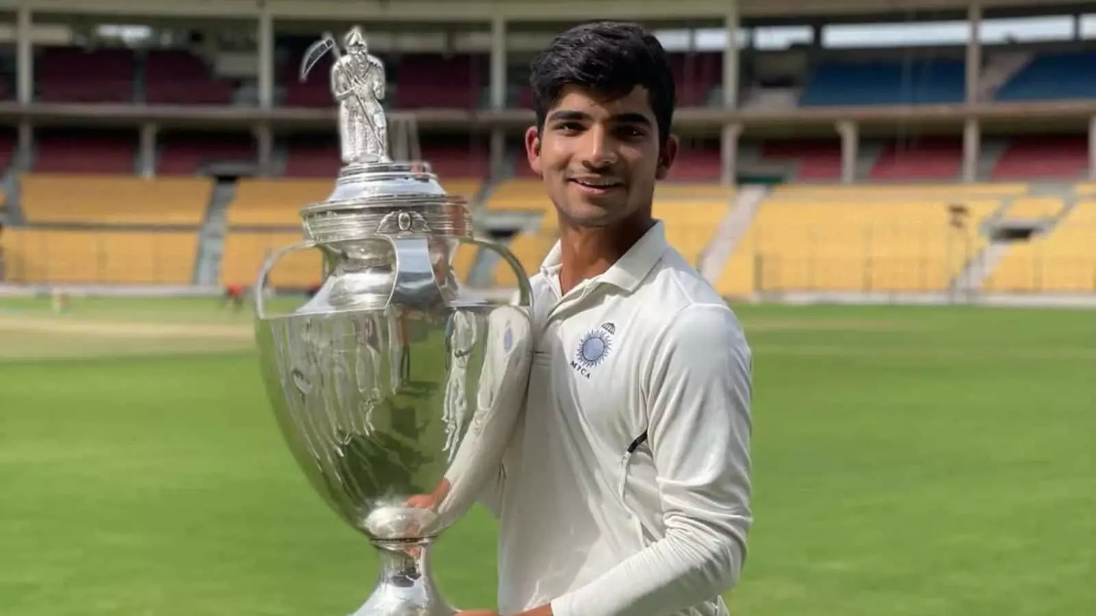 सफेद जर्सी पहने क्रिकेटर अक्षत रघुवंशी क्रिकेट स्टेडियम में चांदी की ट्रॉफी पकड़े हुए मुस्कुरा रहे हैं। सफेद जर्सी पहने क्रिकेटर अक्षत रघुवंशी क्रिकेट स्टेडियम में चांदी की ट्रॉफी पकड़े हुए मुस्कुरा रहे हैं।