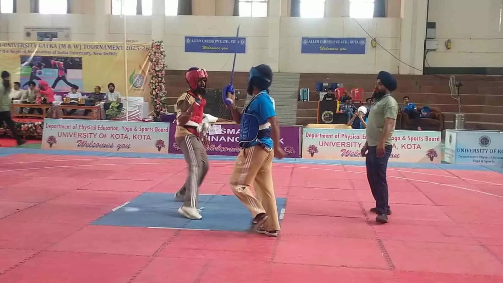 खेल के मैदान में नीली और भूरी जर्सी पहने दो खिलाड़ी कोटा विश्वविद्यालय में गतका प्रतियोगिता के दौरान मुकाबला कर रहे हैं। खेल के मैदान में नीली और भूरी जर्सी पहने दो खिलाड़ी कोटा विश्वविद्यालय में गतका प्रतियोगिता के दौरान मुकाबला कर रहे हैं।