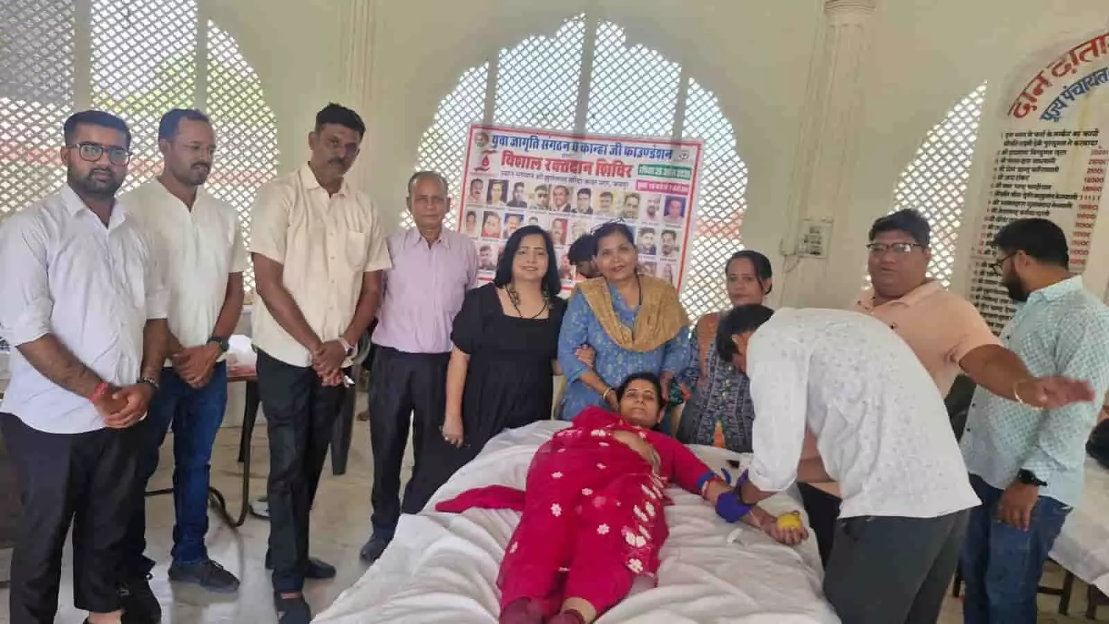 जयपुर के झूलेलाल मंदिर में आयोजित रक्तदान शिविर के दौरान बेड पर लेटी महिला और खड़े अन्य लोग।