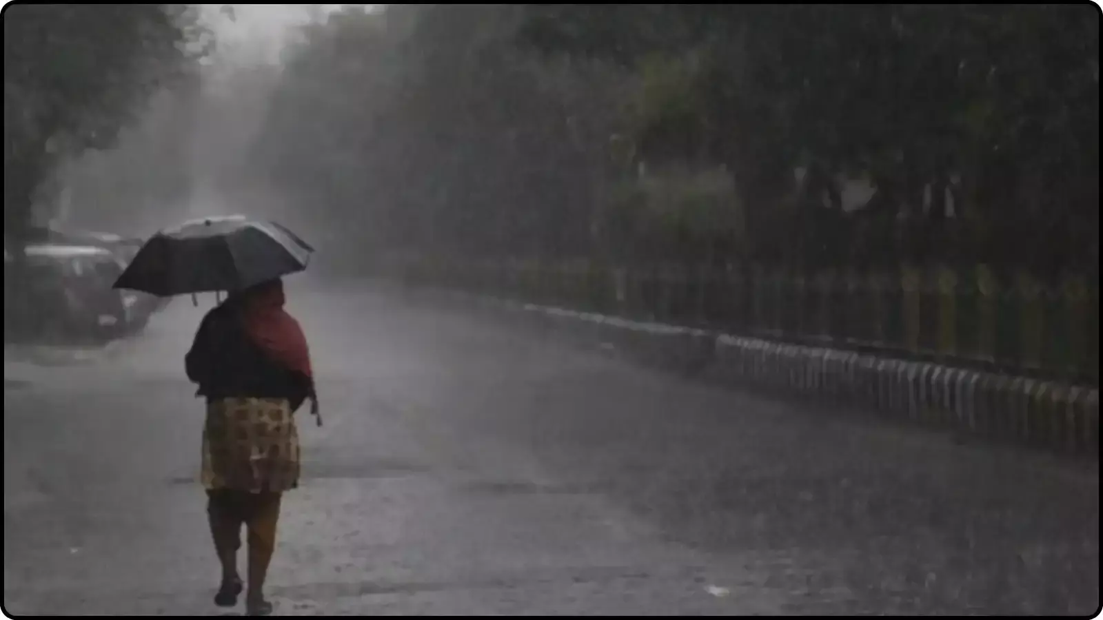 बारिश के दौरान सड़क पर काला छाता लेकर चलती हुई एक महिला।