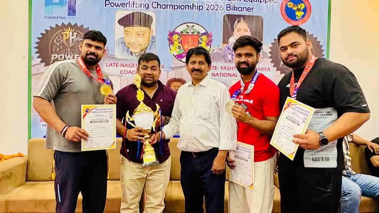 बीकानेर में पावरलिफ्टिंग प्रतियोगिता के विजेता खिलाड़ी ट्रॉफी और प्रमाण पत्र के साथ मंच पर खड़े हैं। बीकानेर में पावरलिफ्टिंग प्रतियोगिता के विजेता खिलाड़ी ट्रॉफी और प्रमाण पत्र के साथ मंच पर खड़े हैं।