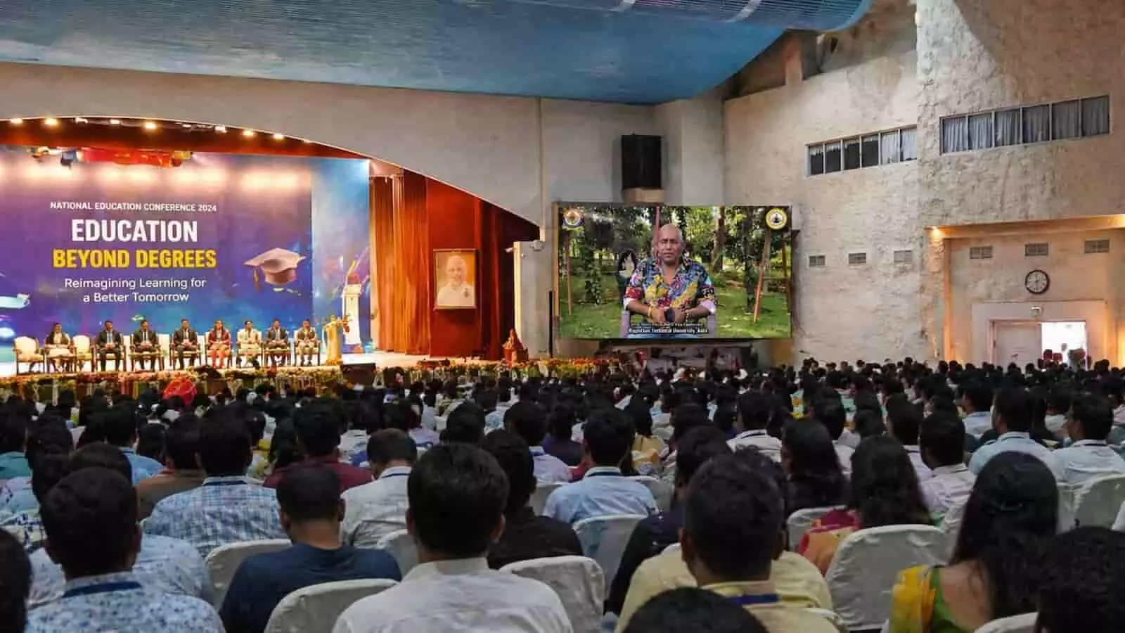 ज्ञान सरोवर के सभागार में शिक्षा सम्मेलन के दौरान स्क्रीन पर संबोधन देते आरटीयू कुलगुरु निमित चौधरी और बैठे हुए प्रतिभागी। ज्ञान सरोवर के सभागार में शिक्षा सम्मेलन के दौरान स्क्रीन पर संबोधन देते आरटीयू कुलगुरु निमित चौधरी और बैठे हुए प्रतिभागी।