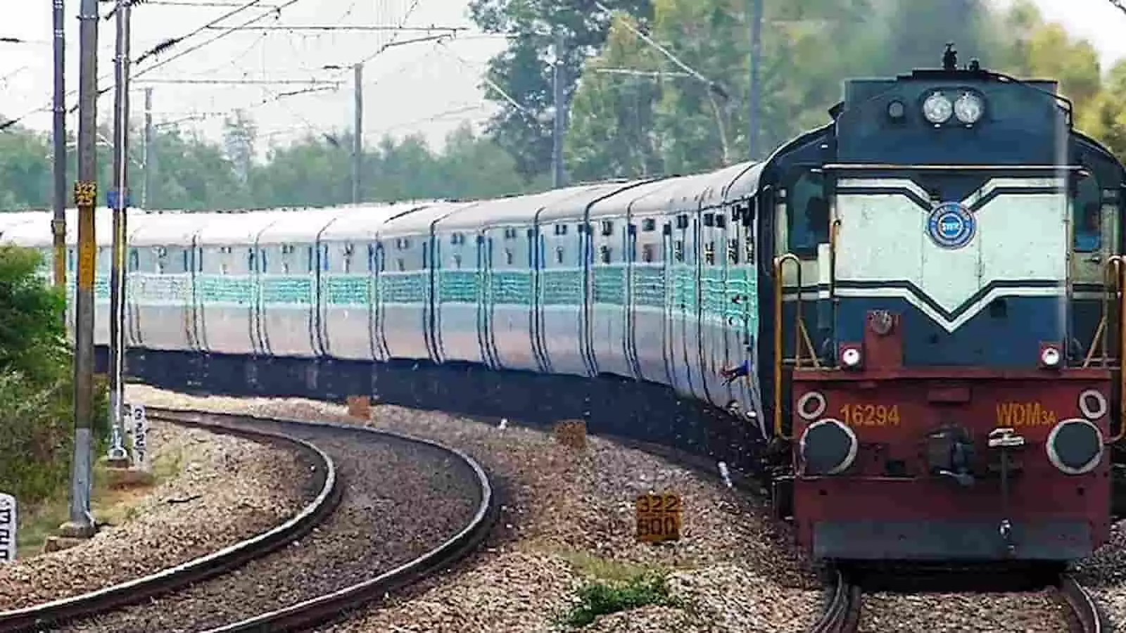 रेलवे ट्रैक पर मुड़ती हुई नीले और सफेद रंग की भारतीय रेलगाड़ी जिसका इंजन ट्रैक पर आगे बढ़ रहा है।