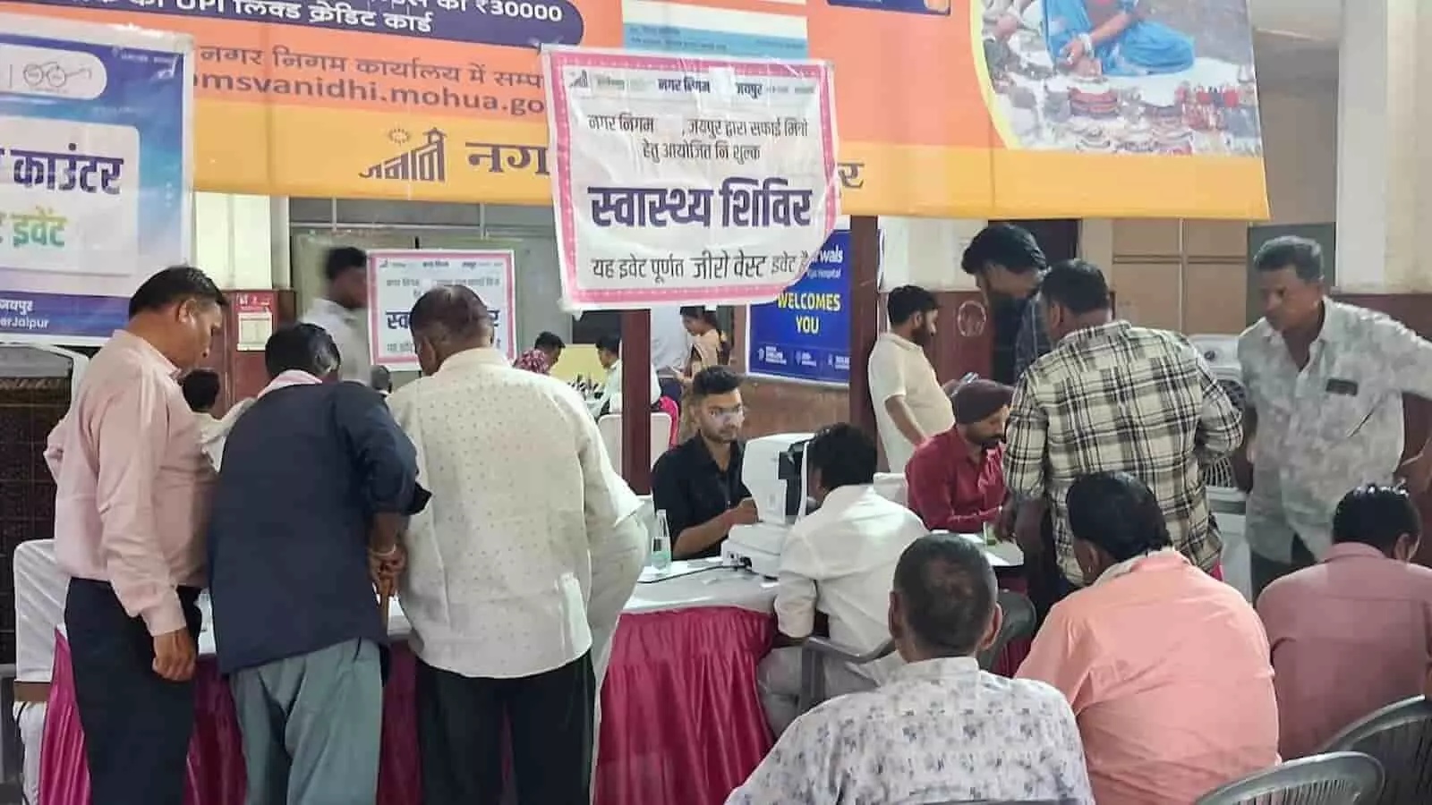 जयपुर नगर निगम मुख्यालय में मशीन से आँखों की जाँच करवाते सफाई कर्मचारी और उपस्थित चिकित्सा दल।
