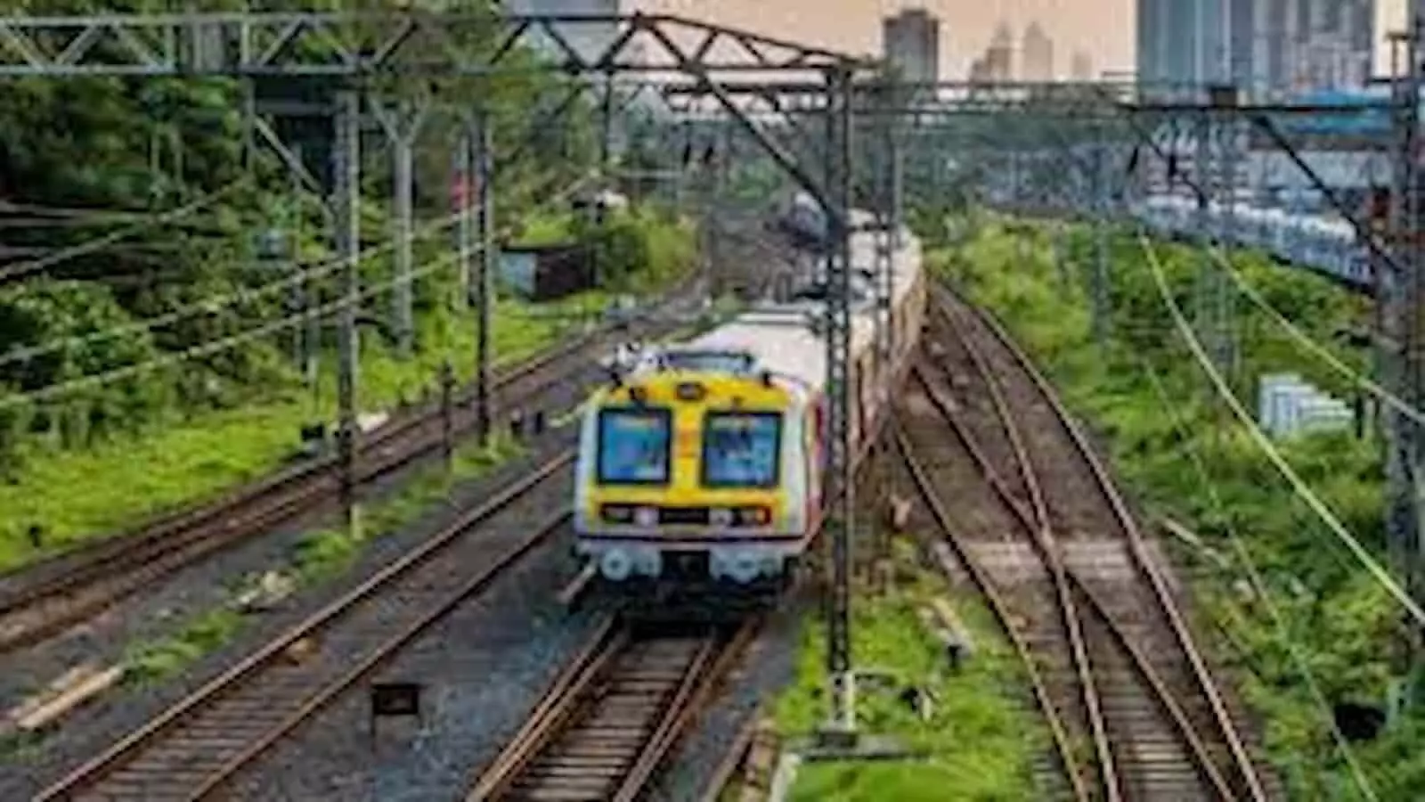 रेलवे ट्रैक पर दौड़ती हुई भारतीय ट्रेन और बिजली के तारों का जाल दिखता हुआ।