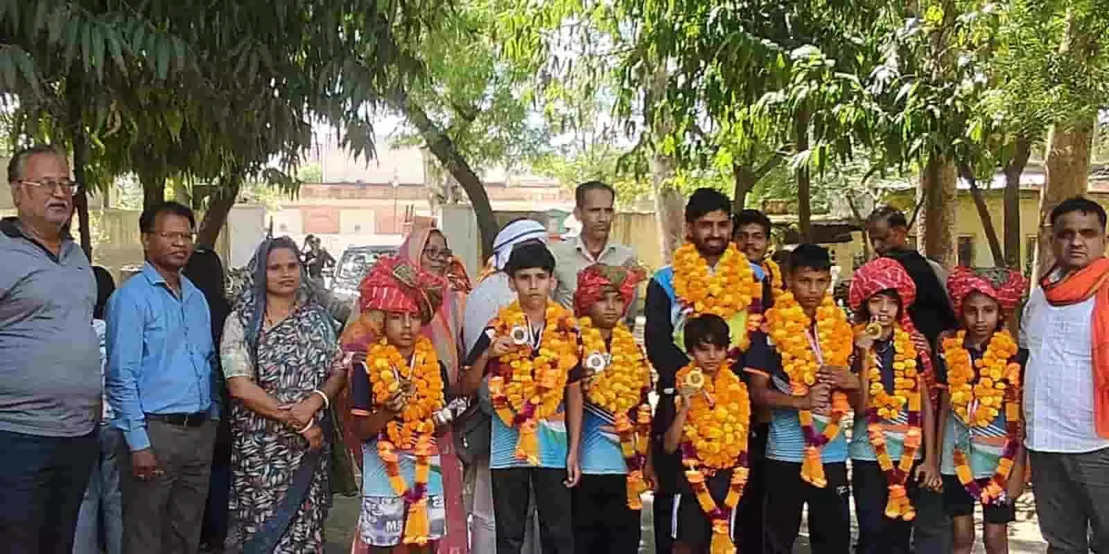 गंगापुर सिटी रेलवे स्टेशन पर पदक विजेता खिलाड़ी और कोच माला पहने हुए दिखाई दे रहे हैं।
