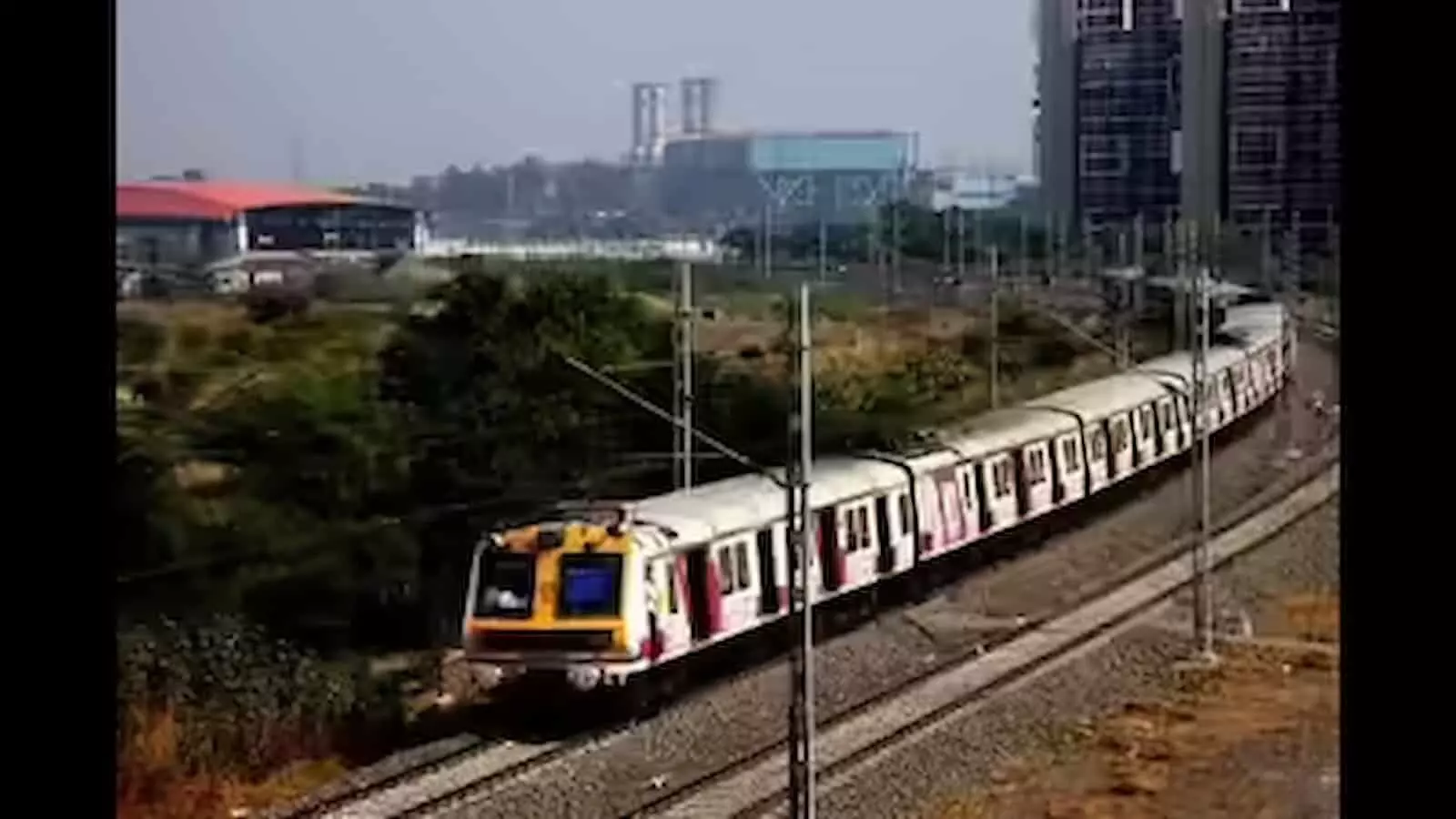 मुंबई में रेलवे ट्रैक पर चलती हुई मध्य रेलवे की लोकल ट्रेन का दृश्य।