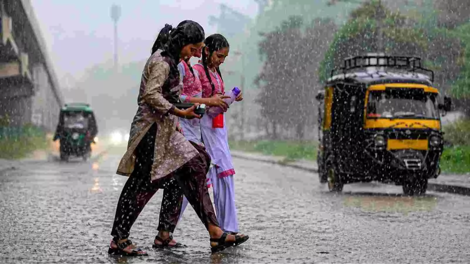 बारिश में भीगते हुए सड़क पार करती छात्राएं और बगल से गुजरता पीला ऑटो रिक्शा। बारिश में भीगते हुए सड़क पार करती छात्राएं और बगल से गुजरता पीला ऑटो रिक्शा।