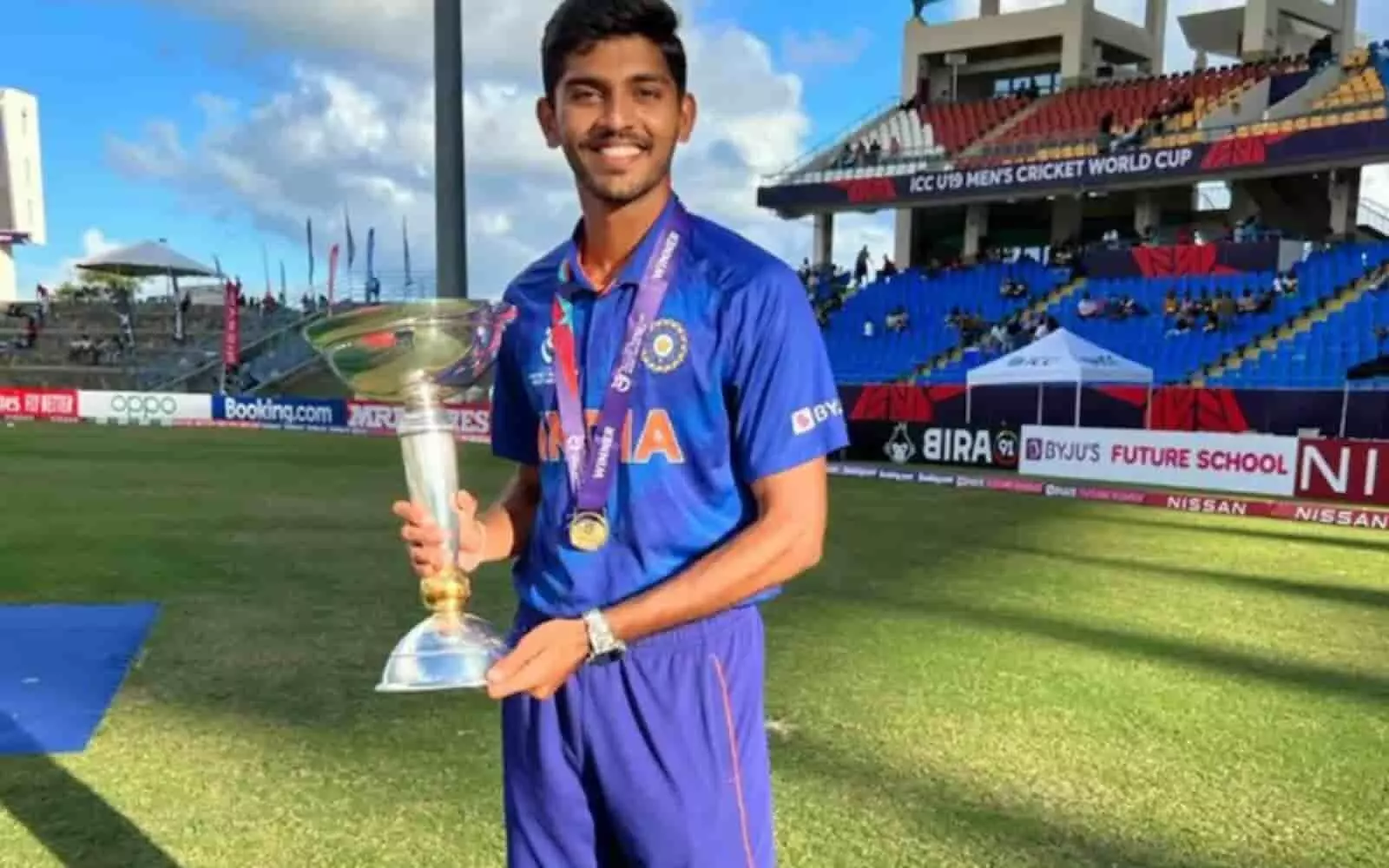क्रिकेट मैदान पर अंडर-19 वर्ल्ड कप ट्रॉफी के साथ भारतीय स्पिनर विक्की ओस्तवाल मुस्कराते हुए।