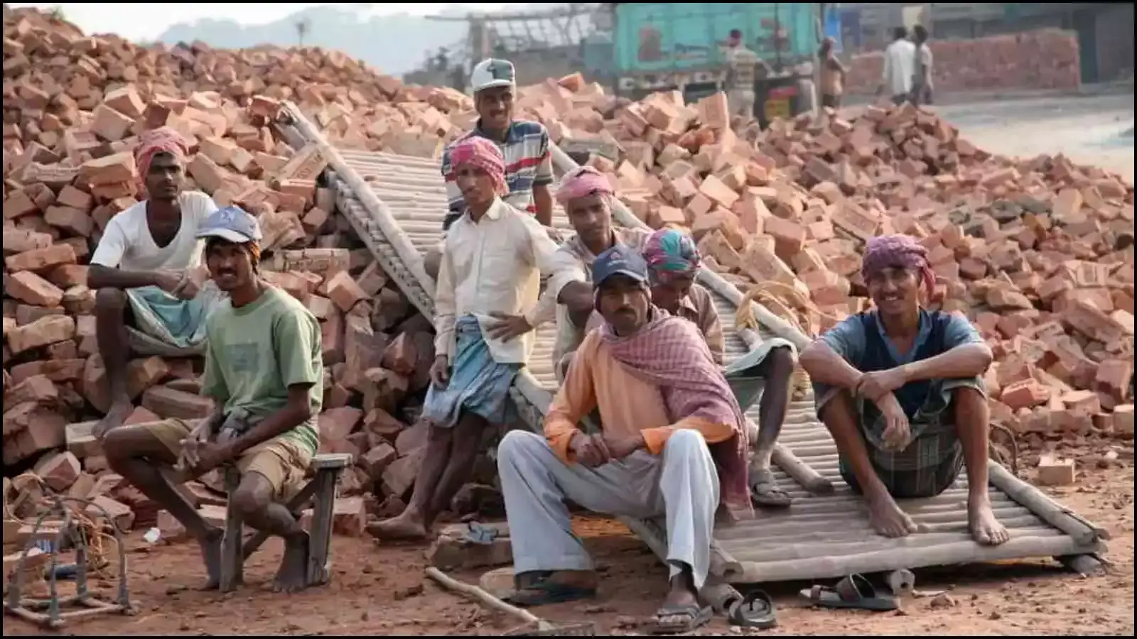 ईंटों के ढेर के पास जमीन पर बैठकर विश्राम करते हुए श्रमिकों का एक समूह। ईंटों के ढेर के पास जमीन पर बैठकर विश्राम करते हुए श्रमिकों का एक समूह।