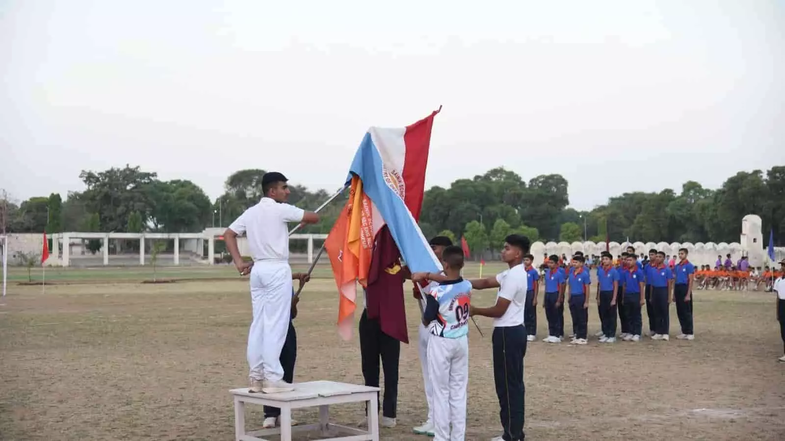 सैनिक स्कूल के खेल मैदान पर उद्घाटन समारोह के दौरान ध्वज पकड़े कैडेट और मार्च पास्ट करते छात्र। सैनिक स्कूल के खेल मैदान पर उद्घाटन समारोह के दौरान ध्वज पकड़े कैडेट और मार्च पास्ट करते छात्र।