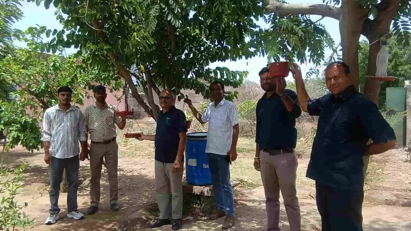 देवरिया के राजकीय विद्यालय परिसर में शिक्षकों द्वारा पक्षियों के लिए पेड़ पर पानी का परिंडा बांधा जा रहा है।