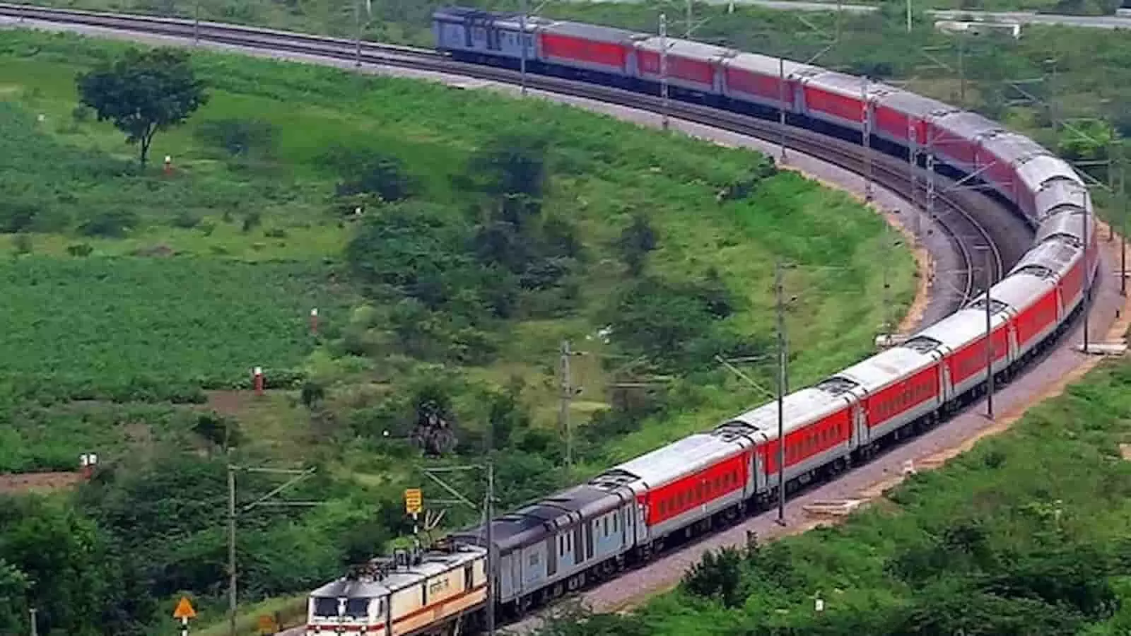 रेलवे ट्रैक पर चलती हुई लाल और नारंगी रंग की अमृत भारत एक्सप्रेस ट्रेन का एरियल व्यू। रेलवे ट्रैक पर चलती हुई लाल और नारंगी रंग की अमृत भारत एक्सप्रेस ट्रेन का एरियल व्यू।