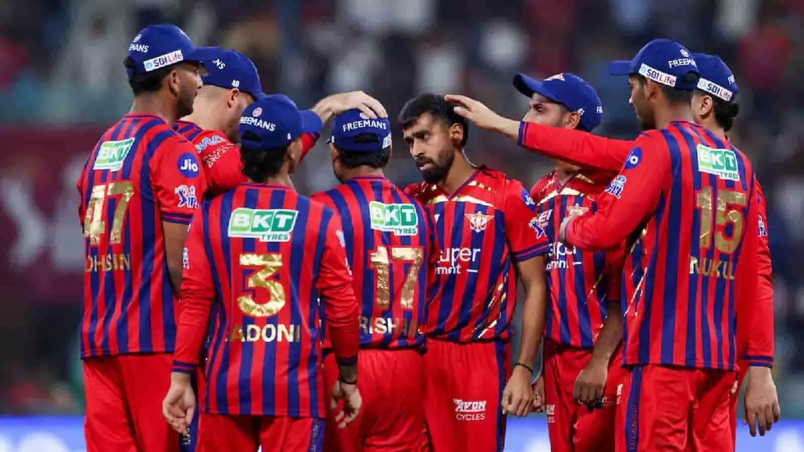 क्रिकेट मैदान पर लखनऊ सुपर जायंट्स के खिलाड़ी लाल नीली जर्सी में एकजुट होकर रणनीति बनाते हुए।