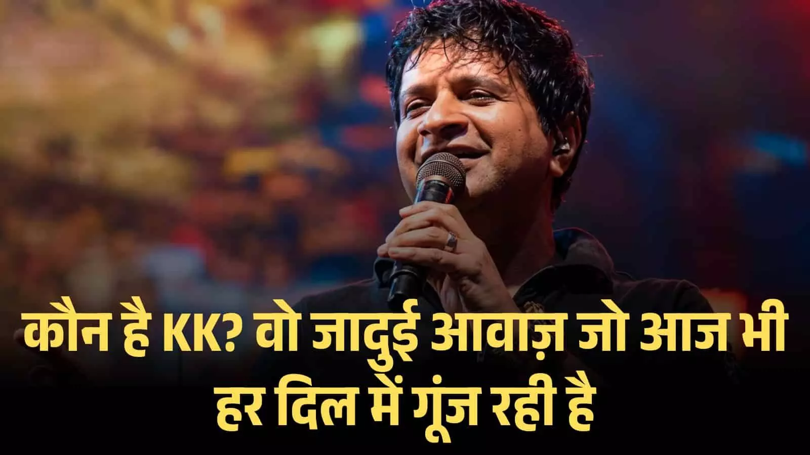 स्टेज पर हाथ में माइक पकड़े हुए मुस्कुराते हुए गायक केके लाइव म्यूज़िक कॉन्सर्ट के दौरान गा रहे हैं।