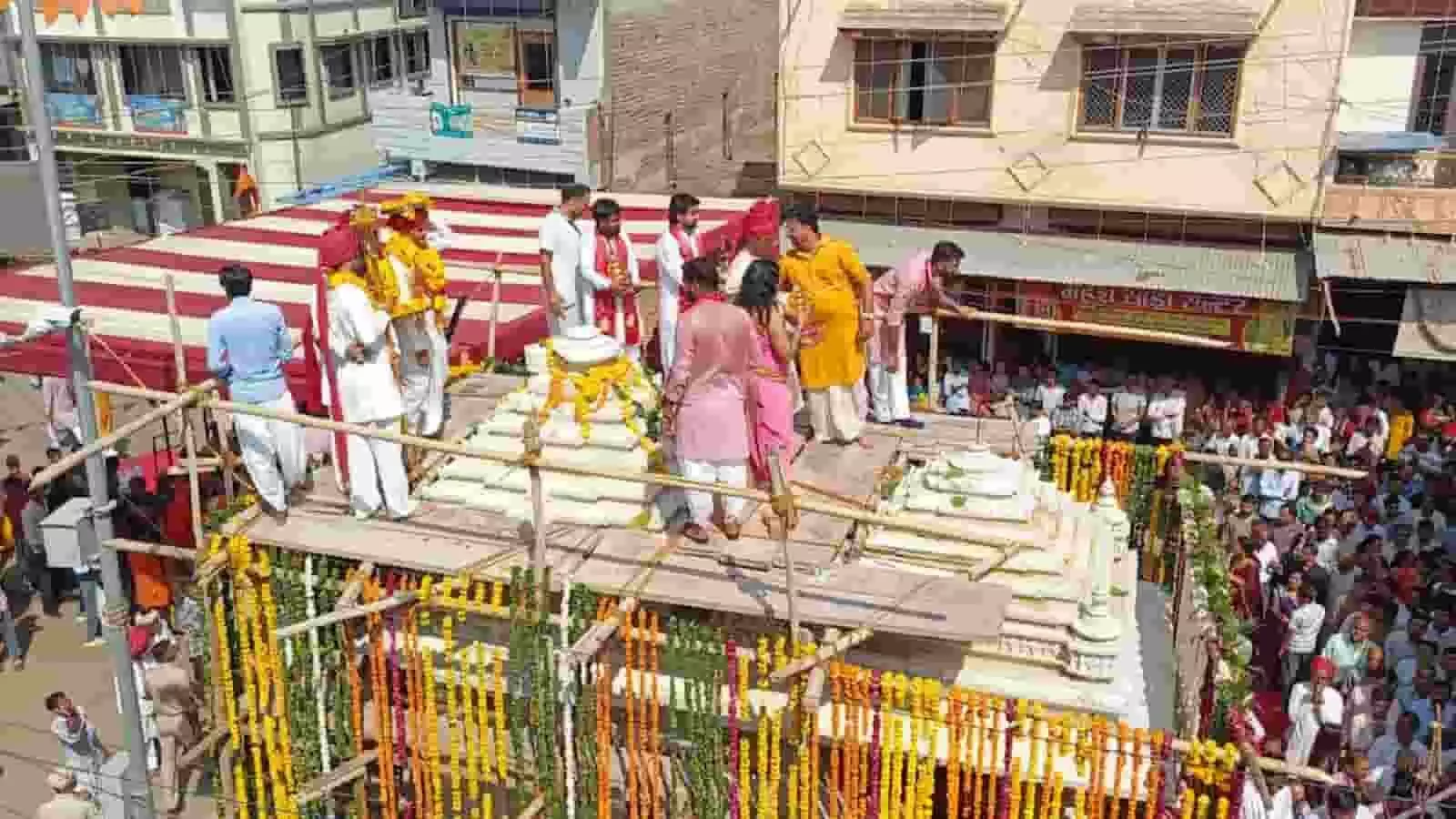 नवनिर्मित अंबे माता मंदिर के शिखर पर अनुष्ठान करते लोग और सजा हुआ मंदिर परिसर। नवनिर्मित अंबे माता मंदिर के शिखर पर अनुष्ठान करते लोग और सजा हुआ मंदिर परिसर।