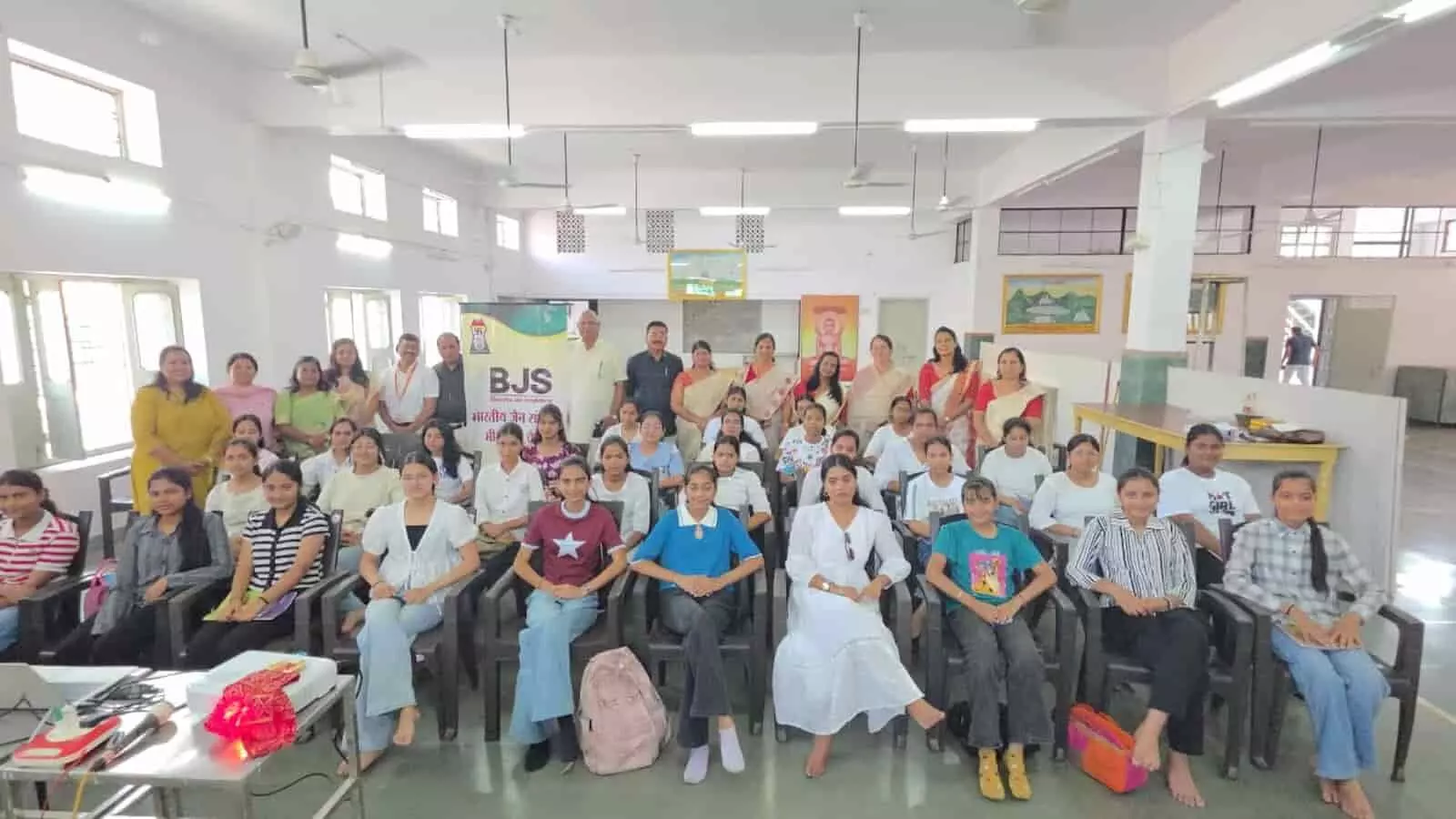 स्वाध्याय भवन भीलवाड़ा में स्मार्ट गर्ल वर्कशॉप के दौरान कुर्सियों पर बैठी प्रतिभागी बेटियां और पीछे खड़े आयोजक।