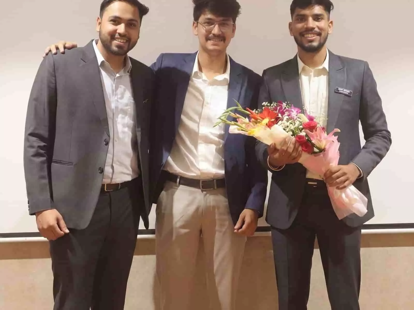 औपचारिक सूट में खड़े नोवॉर्बिस इटस के तीन संस्थापक पुणे में व्यावसायिक कार्यक्रम के दौरान हाथ में बुके लिए हुए।