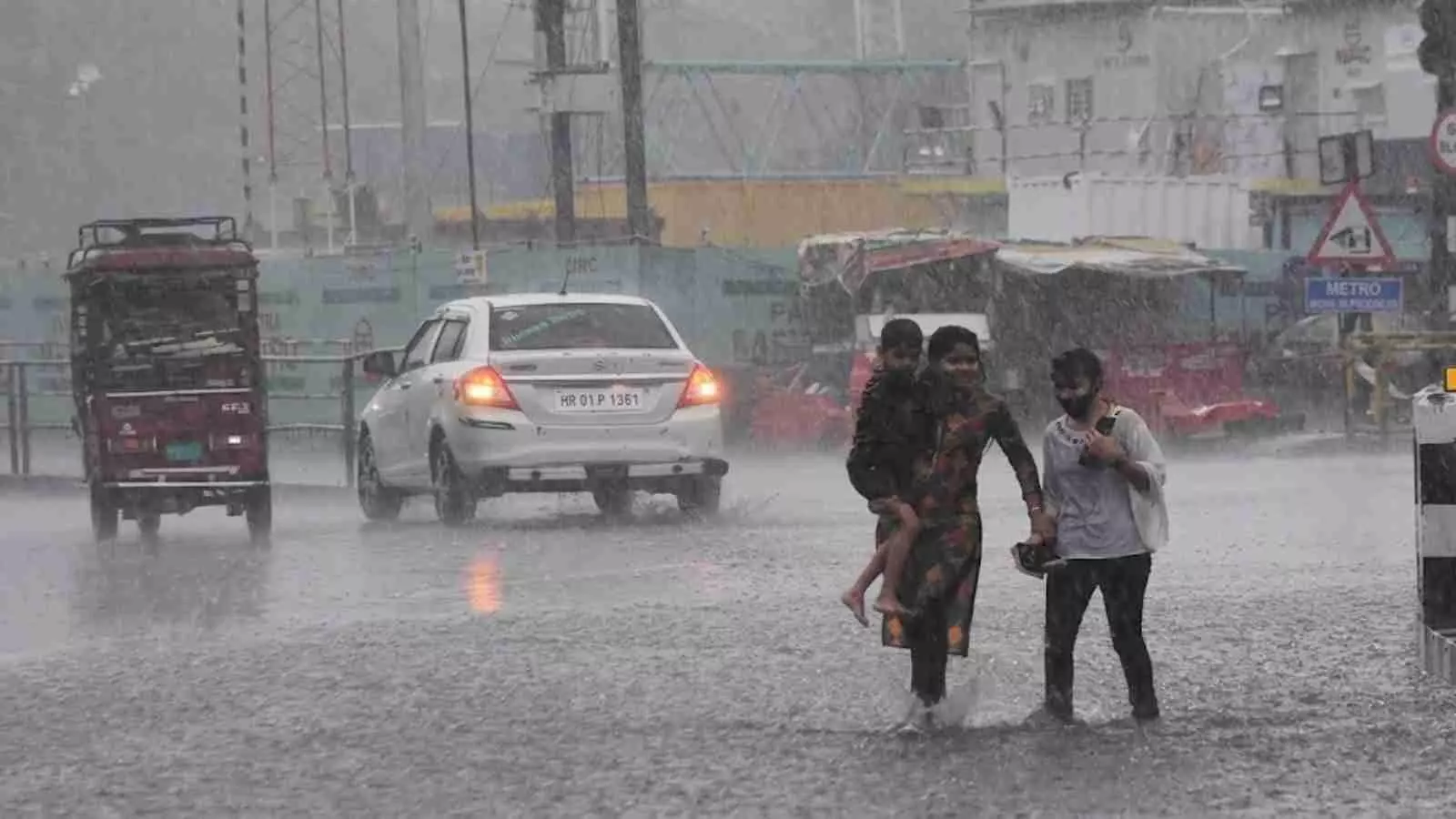 भारी बारिश के बीच जलभराव वाली सड़क पर पैदल चलते लोग और वाहन। भारी बारिश के बीच जलभराव वाली सड़क पर पैदल चलते लोग और वाहन।