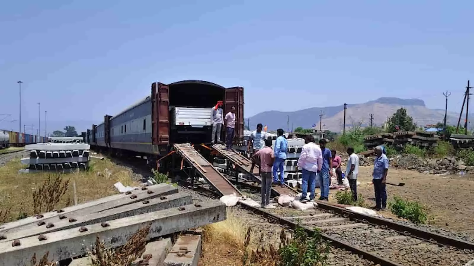 इगतपुरी गुड्स शेड में रेलवे कर्मचारी मालगाड़ी के विशेष वैगनों में नई कारों को लोड कर रहे हैं।