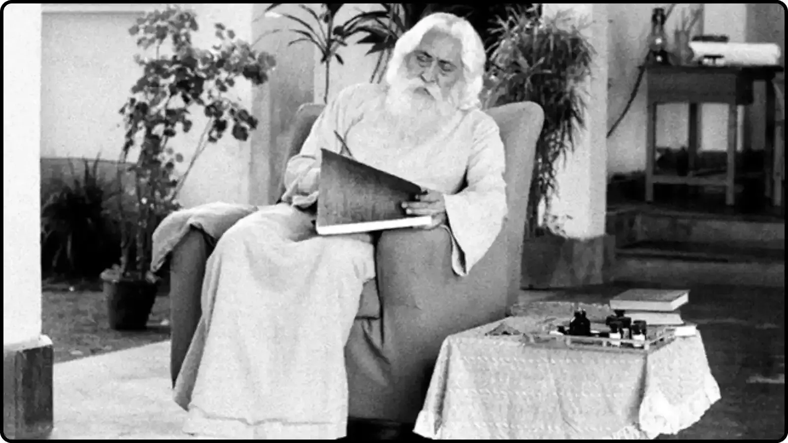 आरामकुर्सी पर बैठे हुए रवीन्द्रनाथ टैगोर शांतिनिकेतन में कागज़ पर कुछ लिखते हुए दिख रहे हैं।