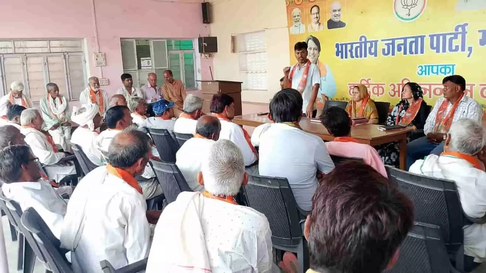 भाजपा ग्रामीण मंडल की बैठक में मंच पर बैठे अतिथि और सामने उपस्थित कार्यकर्ता।