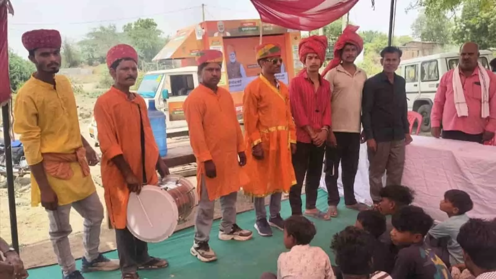 बारां में ग्राम रथ अभियान के दौरान मंच पर खड़े पारंपरिक वेशभूषा में लोक कलाकार और ग्रामीण।