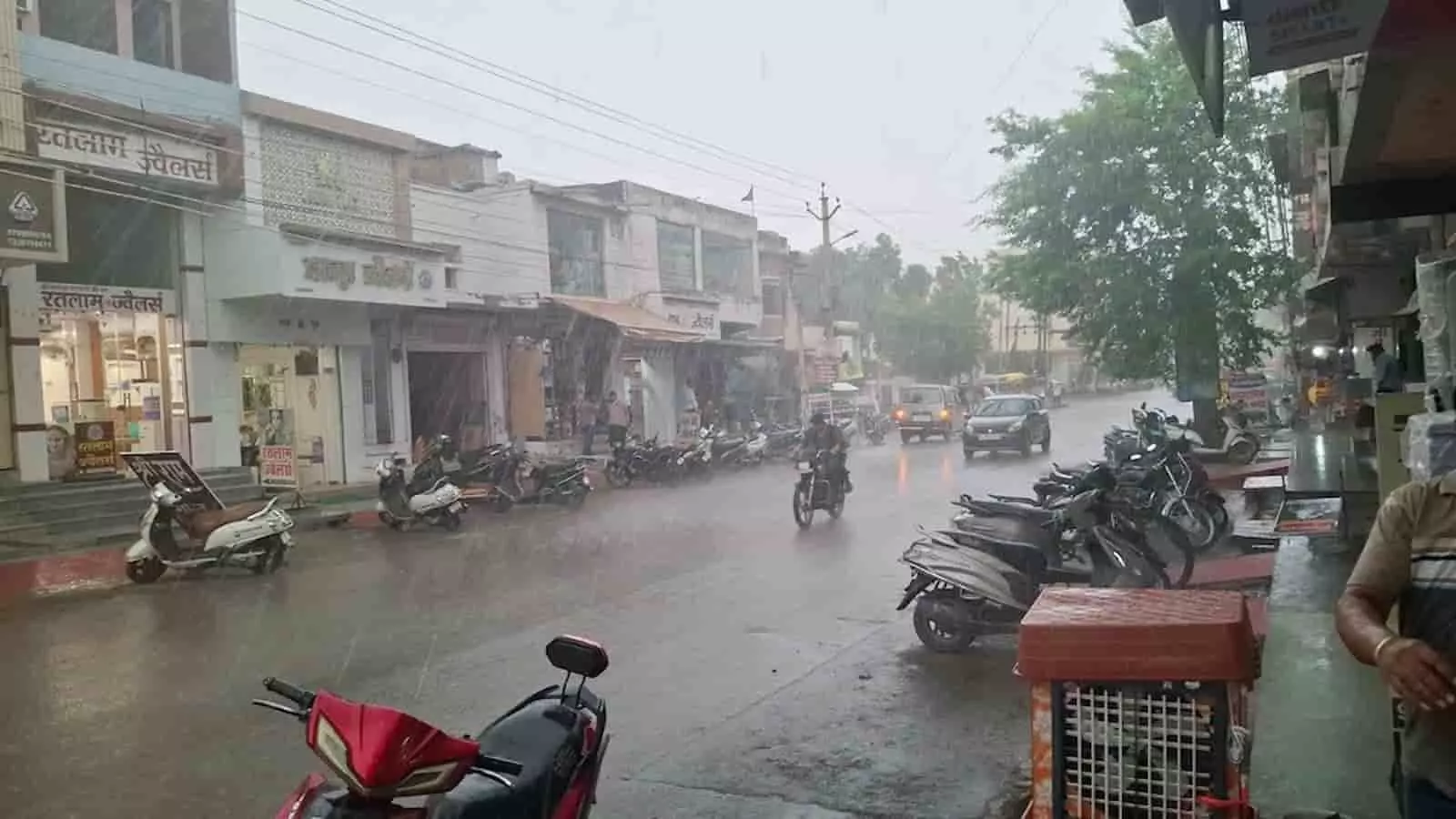 चित्तौड़गढ़ के मुख्य बाजार की सड़क पर मूसलाधार बारिश के बीच चलते वाहन और खड़ी मोटर साइकिलें दिख रही हैं। चित्तौड़गढ़ के मुख्य बाजार की सड़क पर मूसलाधार बारिश के बीच चलते वाहन और खड़ी मोटर साइकिलें दिख रही हैं।