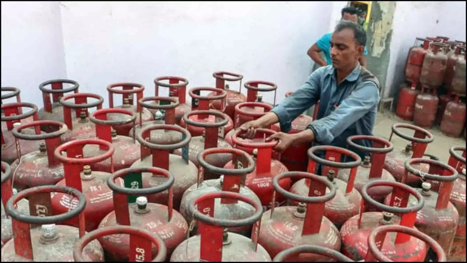 गैस गोदाम में बहुत सारे लाल एलपीजी सिलिंडर और एक कर्मचारी भारत में सुचारू आपूर्ति के संदर्भ में दिख रहा है।