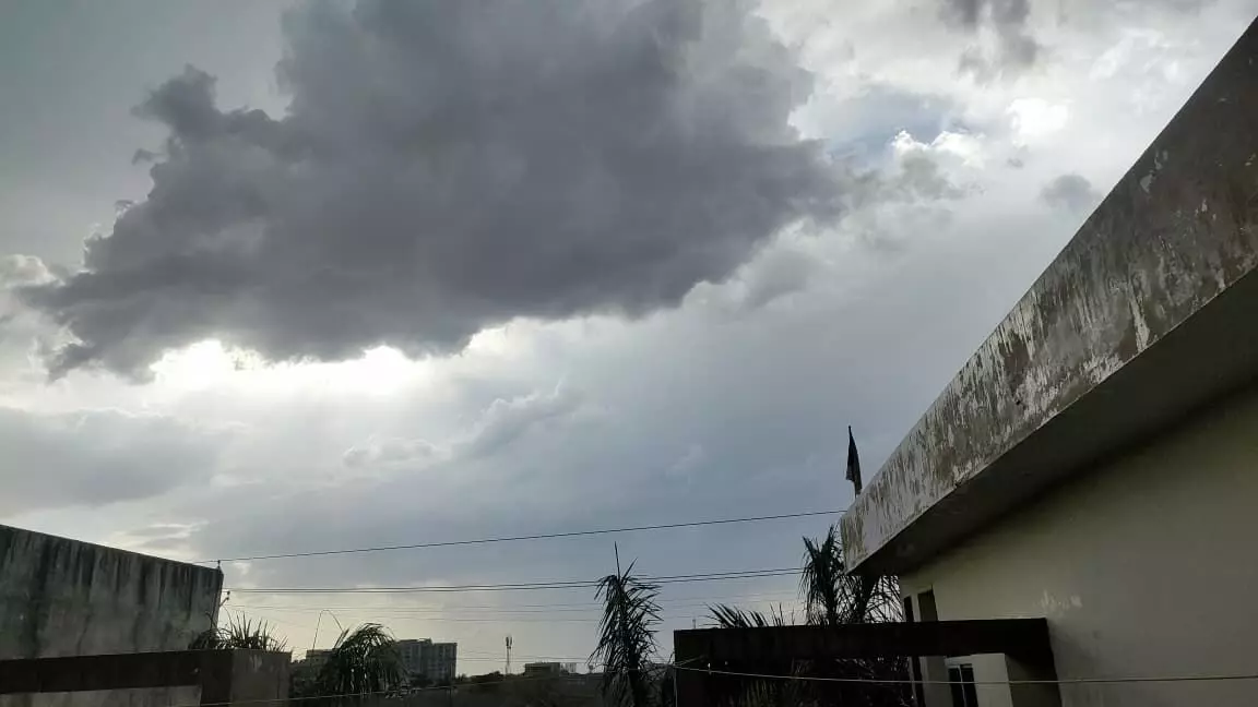 बारां शहर में एक इमारत के ऊपर आसमान में छाए काले बादल और बिजली के तार।