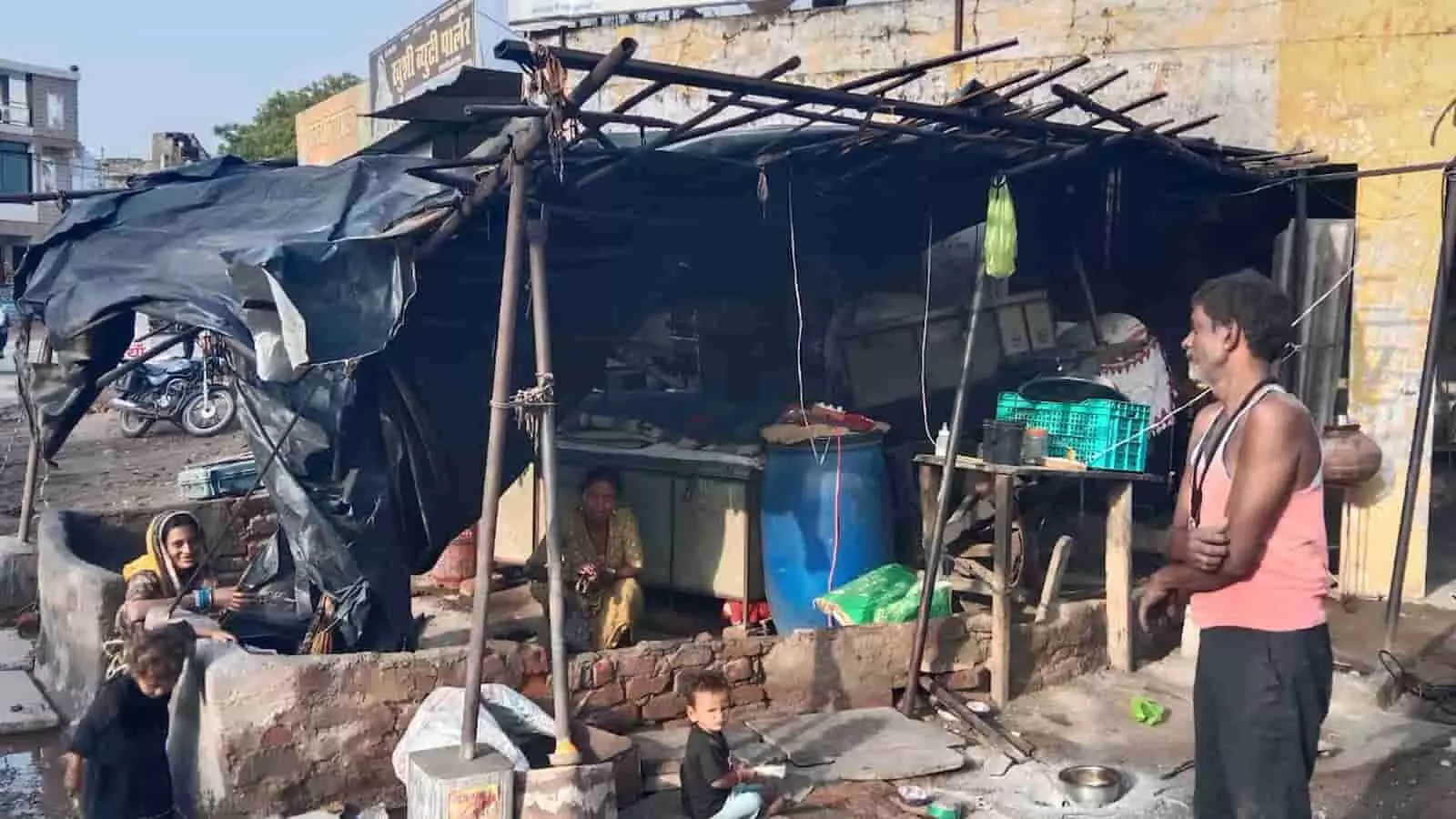 आंधी के कारण क्षतिग्रस्त हुई एक टीन की छत और उसके नीचे खड़े लोग अकोला में मौसम के प्रभाव को दर्शाते हुए।
