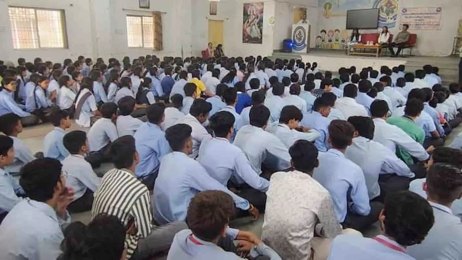 चित्तौड़गढ़ के स्कूल में विधिक साक्षरता शिविर के दौरान जमीन पर बैठे विद्यार्थी और मंच पर उपस्थित अतिथि।