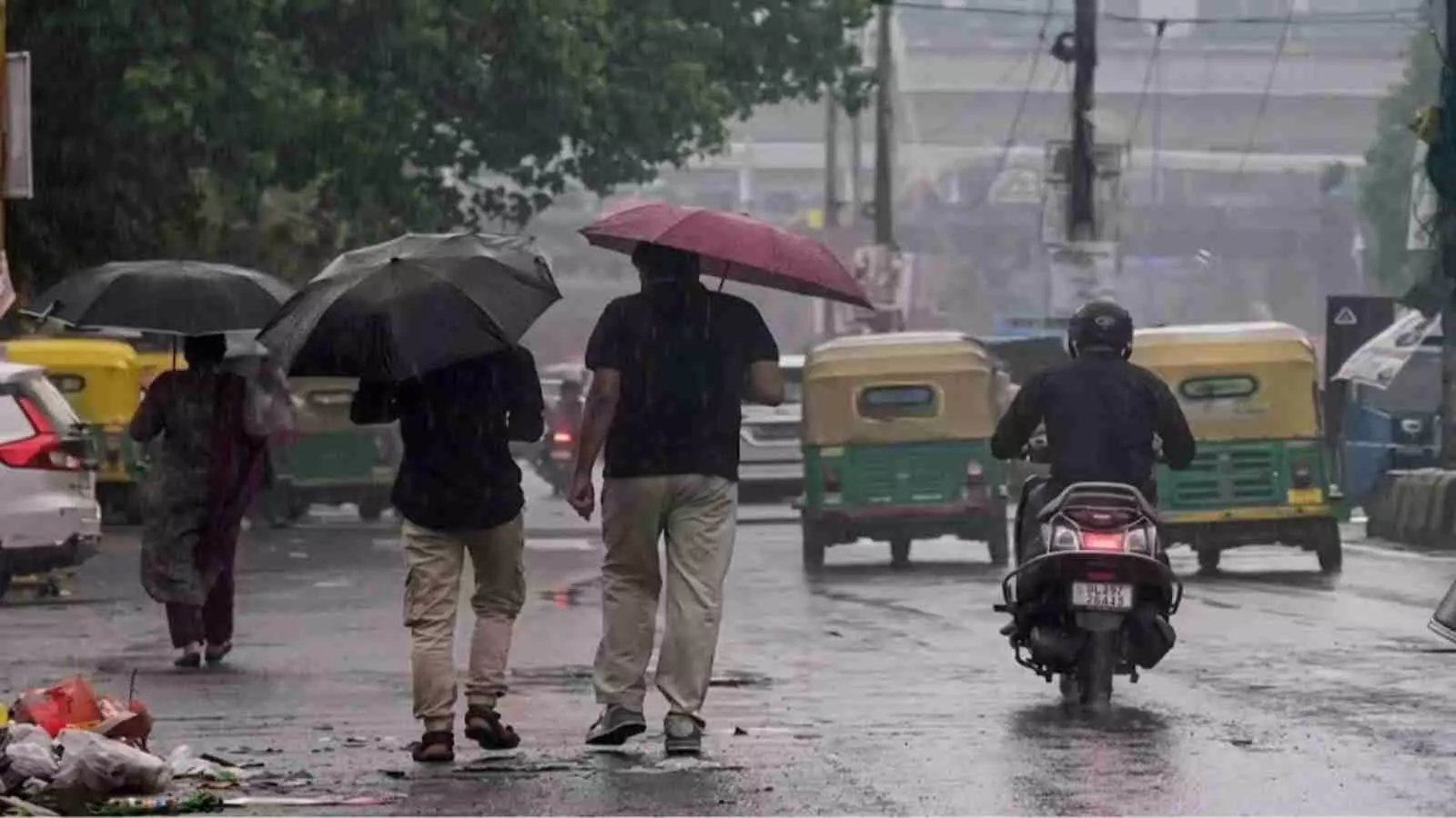 बारिश के दौरान सड़क पर छतरी लेकर चलते लोग और पीछे से आते वाहन दक्षिण भारत मौसम। बारिश के दौरान सड़क पर छतरी लेकर चलते लोग और पीछे से आते वाहन दक्षिण भारत मौसम।