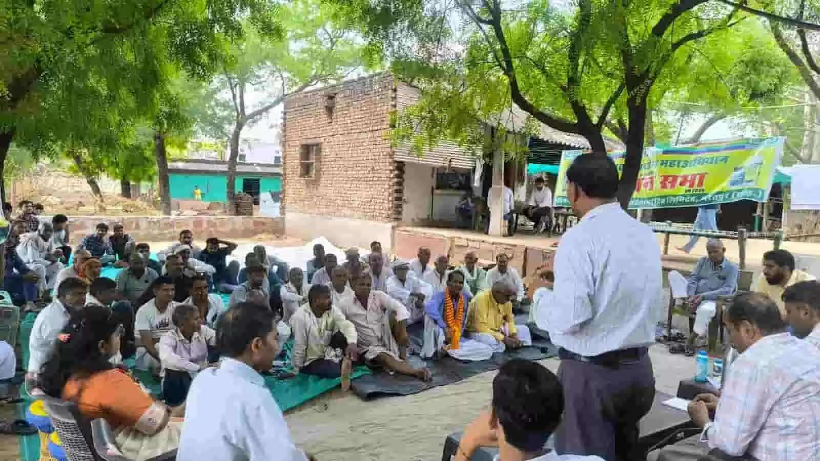 जयकारी गांव में आयोजित किसान सभा में दरी पर बैठे किसानों को संबोधित करते कृषि विशेषज्ञ।