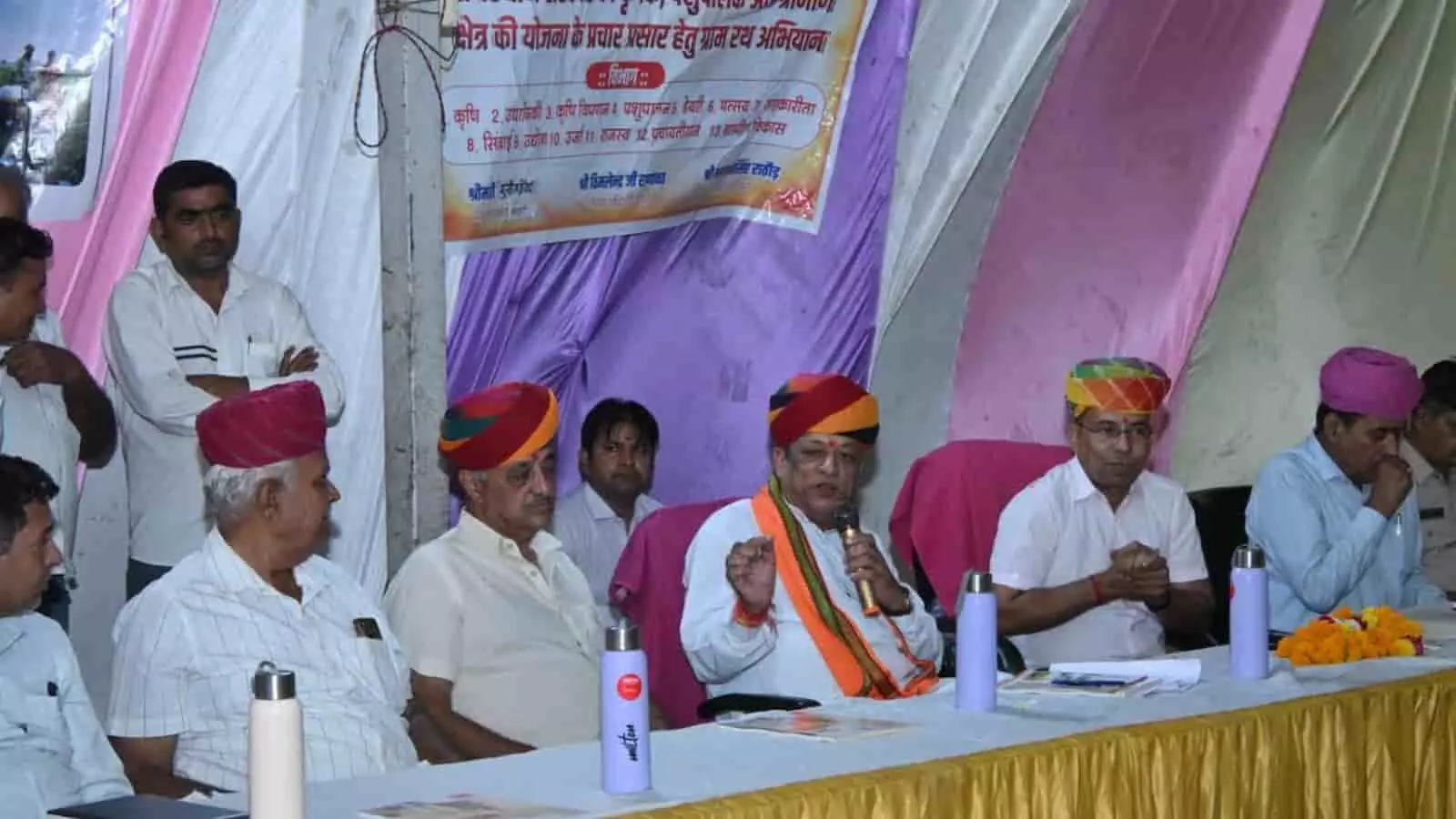 संध्या चौपाल के दौरान मंच पर माइक से ग्रामीणों को संबोधित करते पशुपालन मंत्री जोराराम कुमावत। संध्या चौपाल के दौरान मंच पर माइक से ग्रामीणों को संबोधित करते पशुपालन मंत्री जोराराम कुमावत।