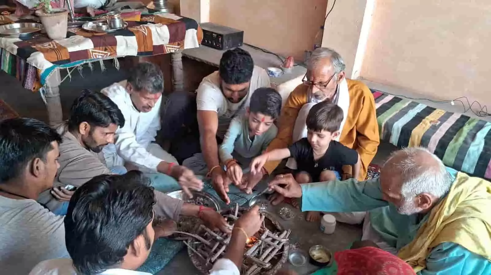 अऊ गाँव के मंदिर में हवन कुंड के चारों ओर बैठकर धार्मिक अनुष्ठान करते हुए ग्रामीण और पुजारी।