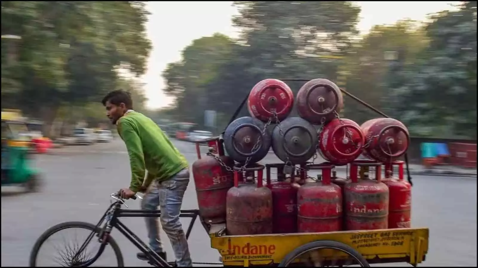 साइकिल रिक्शा पर लदे हुए लाल रंग के घरेलू रसोई गैस सिलेंडर भारत में सड़क पर वितरण के लिए ले जाए जा रहे हैं।