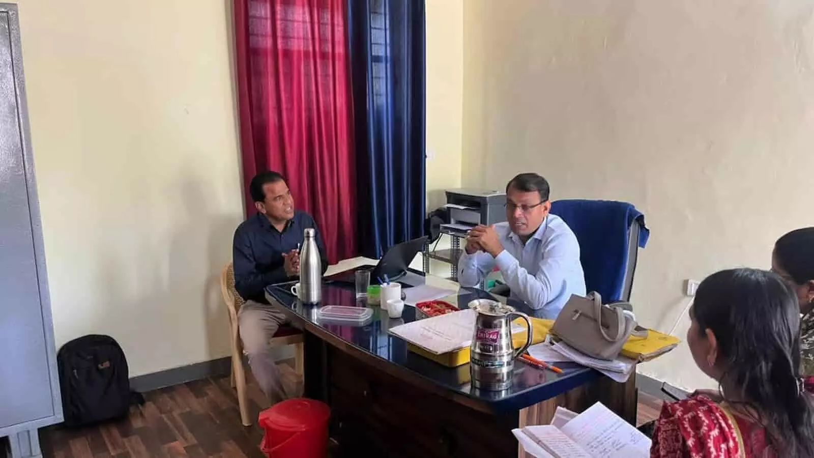 कार्यालय में मेज पर बैठे जिला शिक्षा अधिकारी और प्रधानाचार्य विद्यालय व्यवस्थाओं पर चर्चा करते हुए। कार्यालय में मेज पर बैठे जिला शिक्षा अधिकारी और प्रधानाचार्य विद्यालय व्यवस्थाओं पर चर्चा करते हुए।