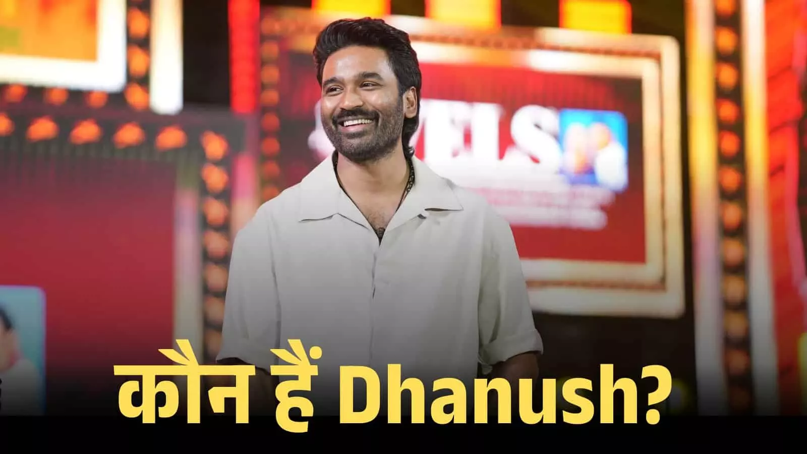 सफेद शर्ट पहने और मुस्कुराते हुए अभिनेता धनुष एक फिल्मी कार्यक्रम के मंच पर खड़े दिखाई दे रहे हैं। सफेद शर्ट पहने और मुस्कुराते हुए अभिनेता धनुष एक फिल्मी कार्यक्रम के मंच पर खड़े दिखाई दे रहे हैं।