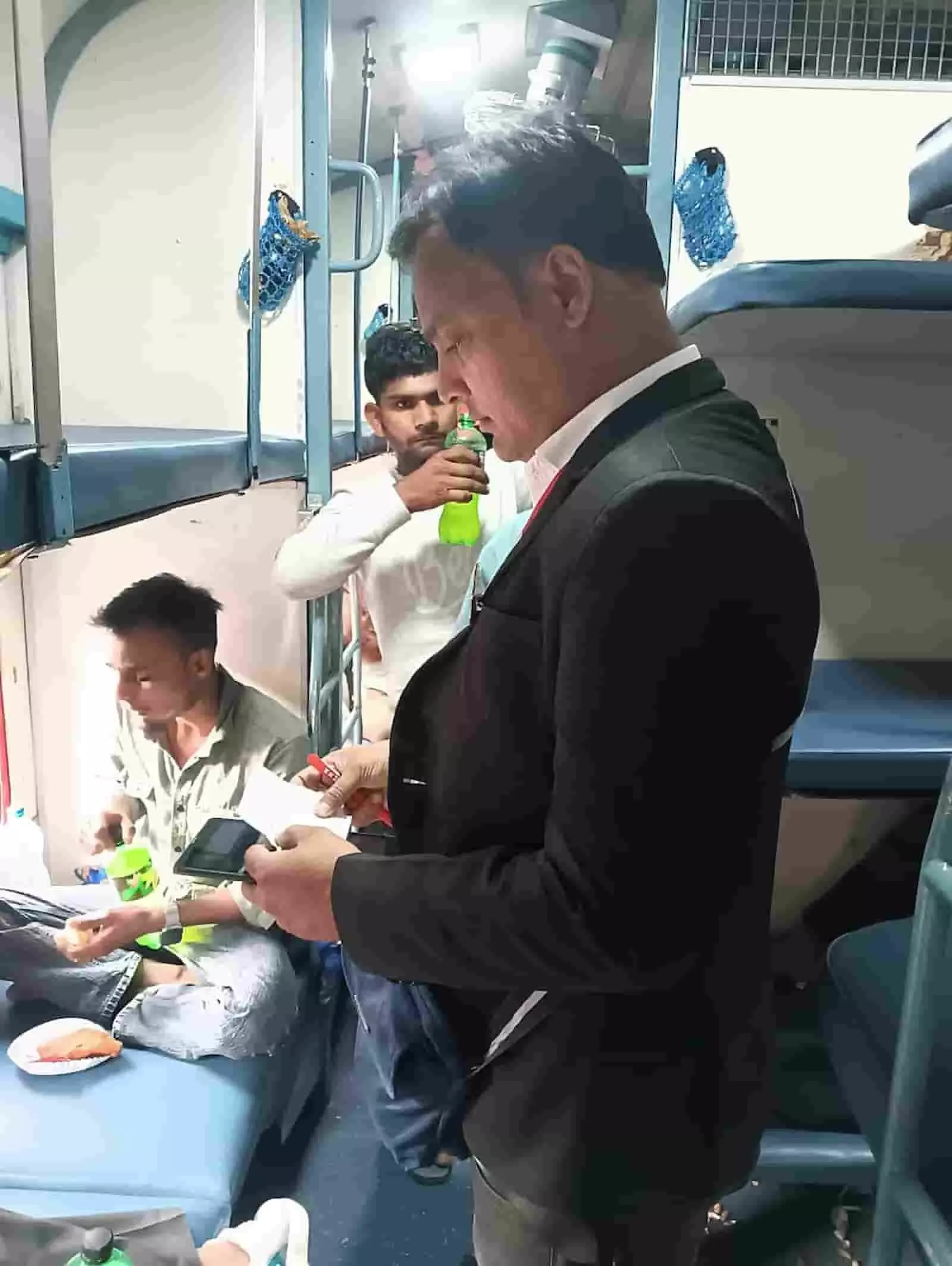 ट्रेन के कोच में यात्रियों के टिकट और दस्तावेजों की जांच करता रेलवे टिकट निरीक्षक।