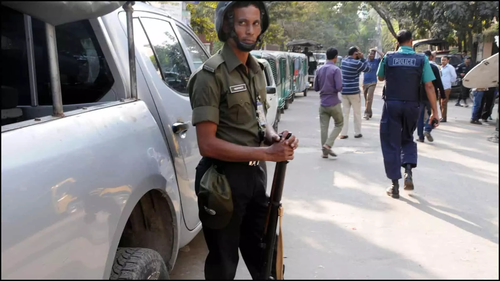 वर्दी में तैनात सुरक्षाकर्मी और पुलिस बल ढाका की सड़क पर सुरक्षा निगरानी करते हुए।