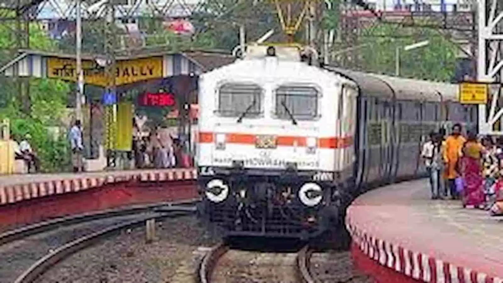 रेलवे स्टेशन के प्लेटफॉर्म पर आती हुई ट्रेन और पटरी के पास खड़े यात्री। रेलवे स्टेशन के प्लेटफॉर्म पर आती हुई ट्रेन और पटरी के पास खड़े यात्री।