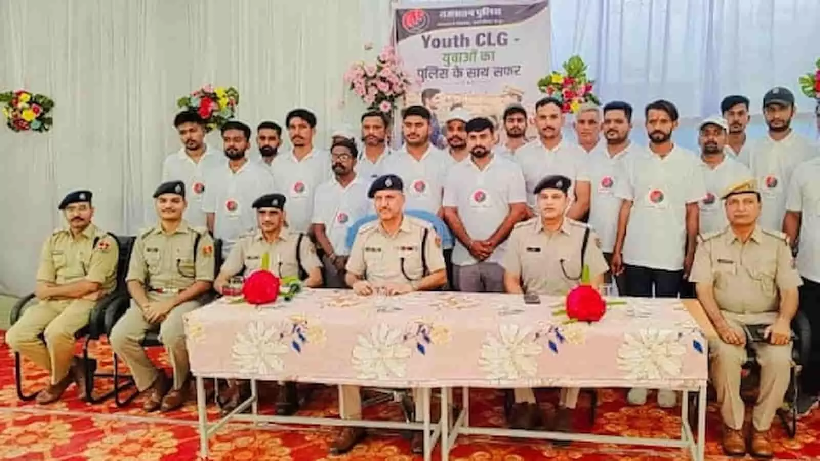 रायपुर पुलिस थाने में यूथ सीएलजी बैठक के दौरान मेज के पीछे बैठे पुलिस अधिकारी और खड़े युवा सदस्य। रायपुर पुलिस थाने में यूथ सीएलजी बैठक के दौरान मेज के पीछे बैठे पुलिस अधिकारी और खड़े युवा सदस्य।