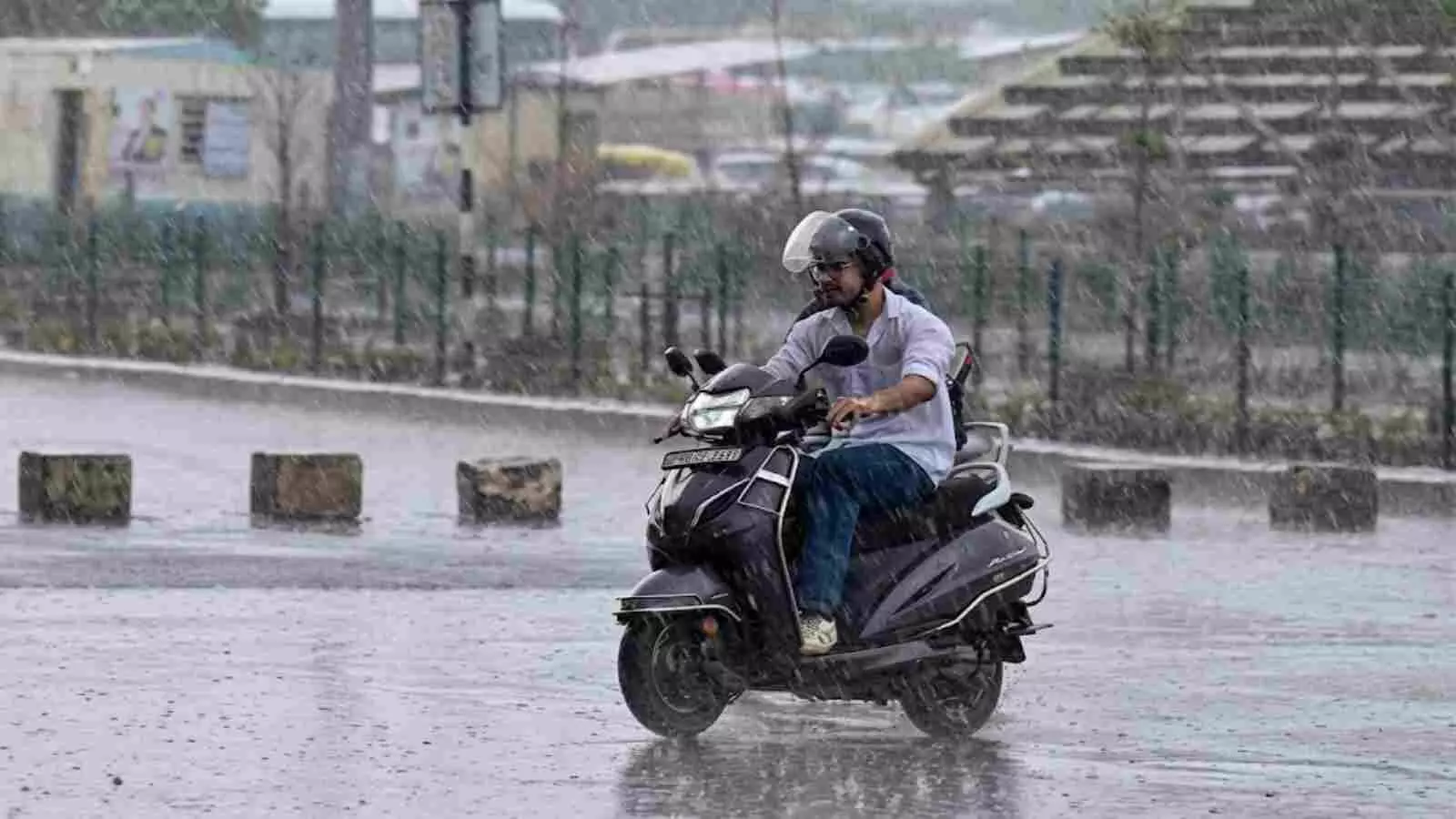 दिल्ली की सड़क पर बारिश के दौरान हेलमेट पहनकर स्कूटर चलाता व्यक्ति। दिल्ली की सड़क पर बारिश के दौरान हेलमेट पहनकर स्कूटर चलाता व्यक्ति।