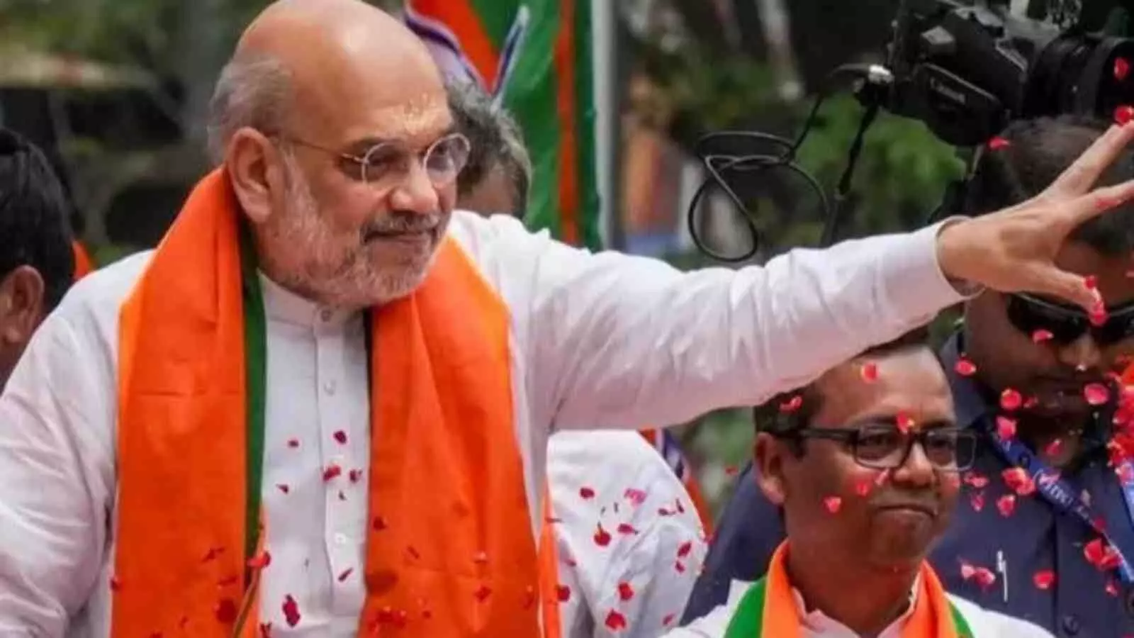 केंद्रीय गृह मंत्री अमित शाह कोलकाता में भाजपा समर्थकों की भीड़ के बीच हाथ हिलाकर अभिवादन कर रहे हैं।