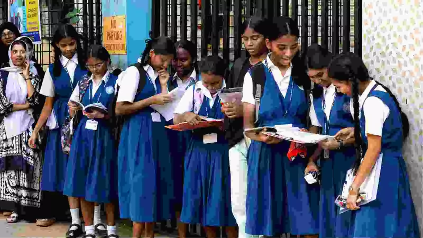 नीली स्कूल यूनिफॉर्म पहने छात्राओं का समूह पुणे में परीक्षा परिणाम देखने के बाद किताबें लिए हुए चर्चा कर रहा है।