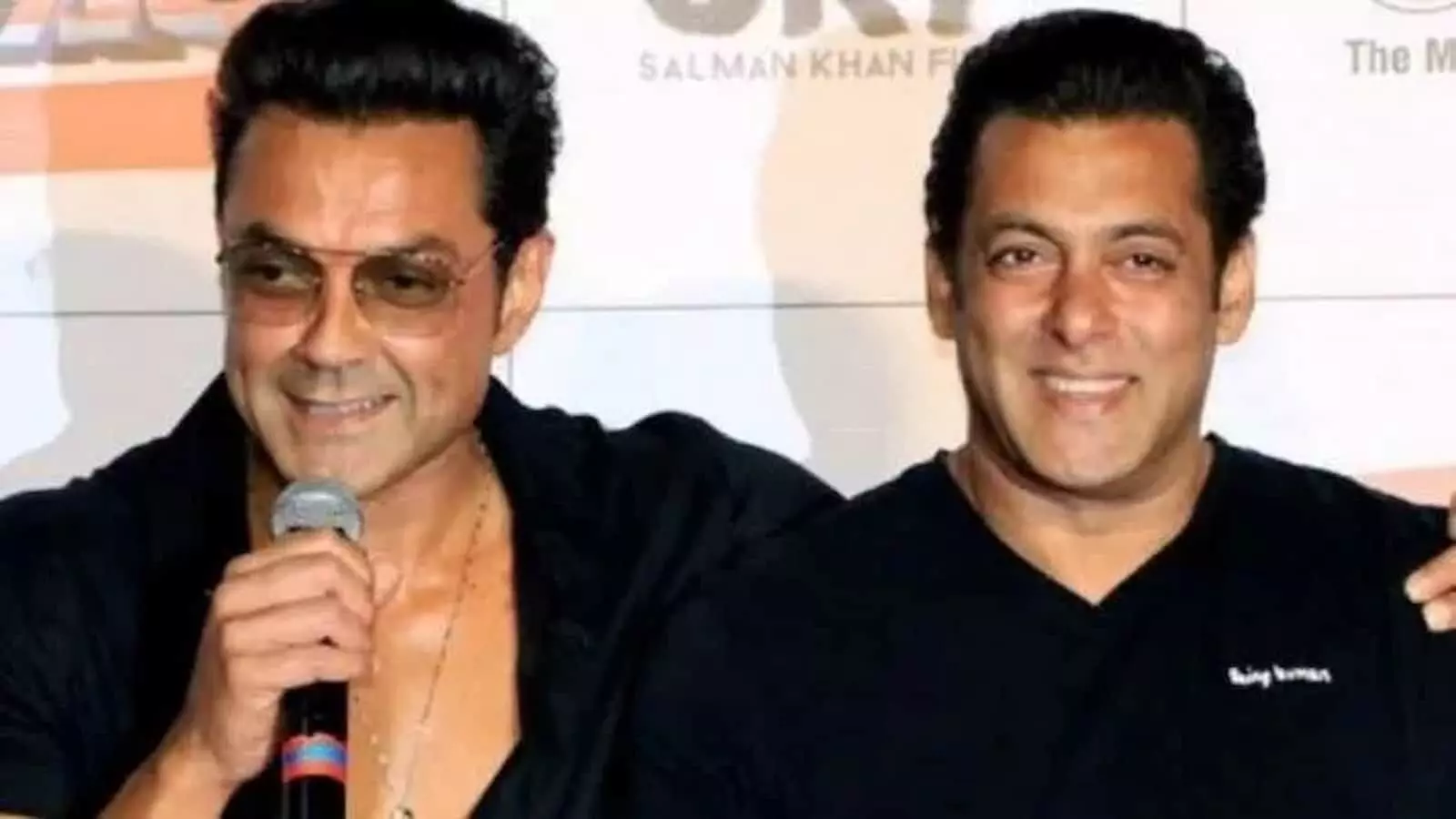 माइक पकड़े हुए बॉबी देओल और उनके साथ खड़े सलमान खान एक इवेंट के दौरान। माइक पकड़े हुए बॉबी देओल और उनके साथ खड़े सलमान खान एक इवेंट के दौरान।