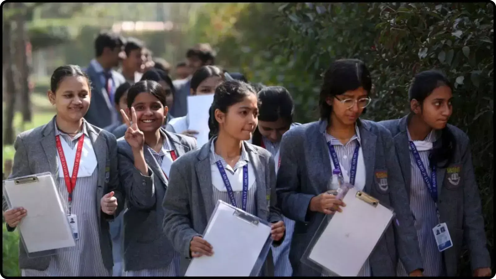 स्कूल यूनिफॉर्म पहने छात्राओं का समूह हाथ में क्लिपबोर्ड लिए सड़क पर चलते हुए दिखाई दे रहा है।