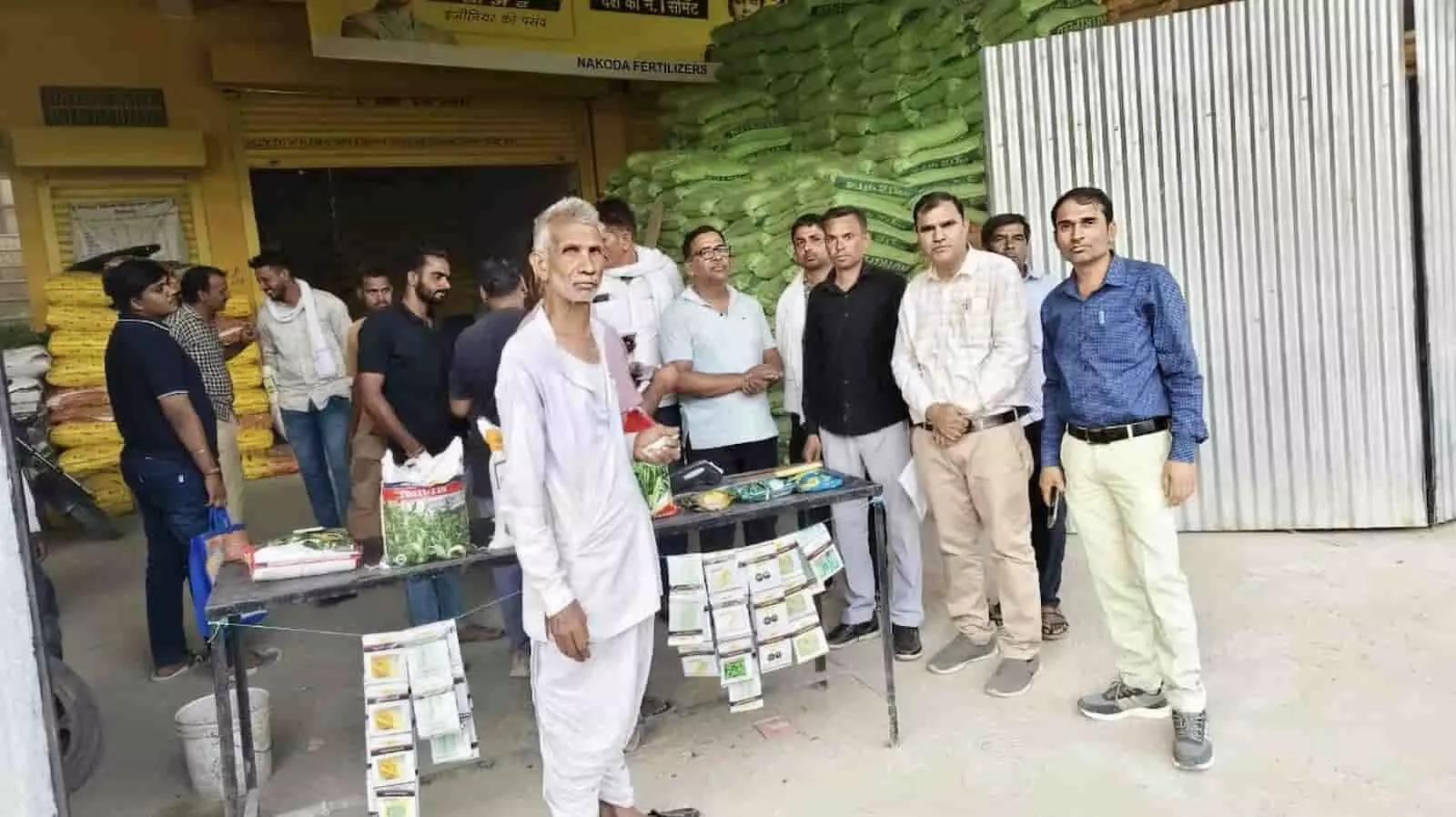 डूंगला में उर्वरक की दुकान के बाहर जांच करते कृषि विभाग के अधिकारी और उपस्थित ग्रामीण।