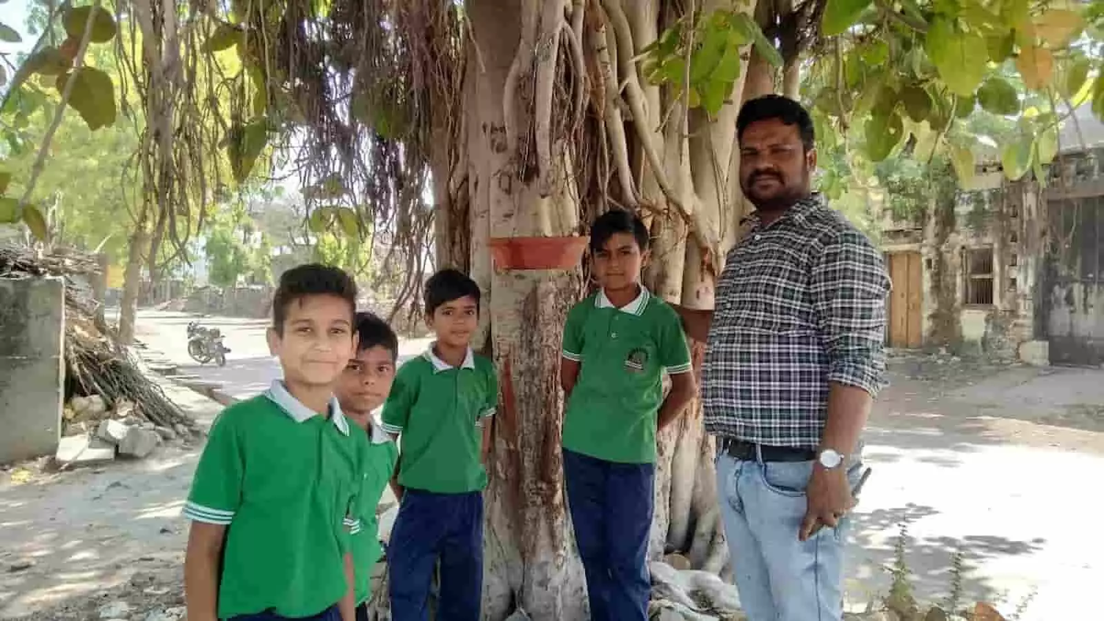 गांधी पब्लिक स्कूल के बच्चे और शिक्षक पेड़ पर पक्षियों के लिए मिट्टी का परिंडा बांधते हुए।